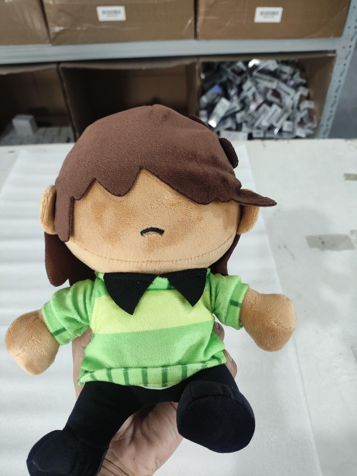 Close-up of the Kris Dreemurr plush head showing its auburn bangs casting a slight shadow over the face and embroidered neutral expression.