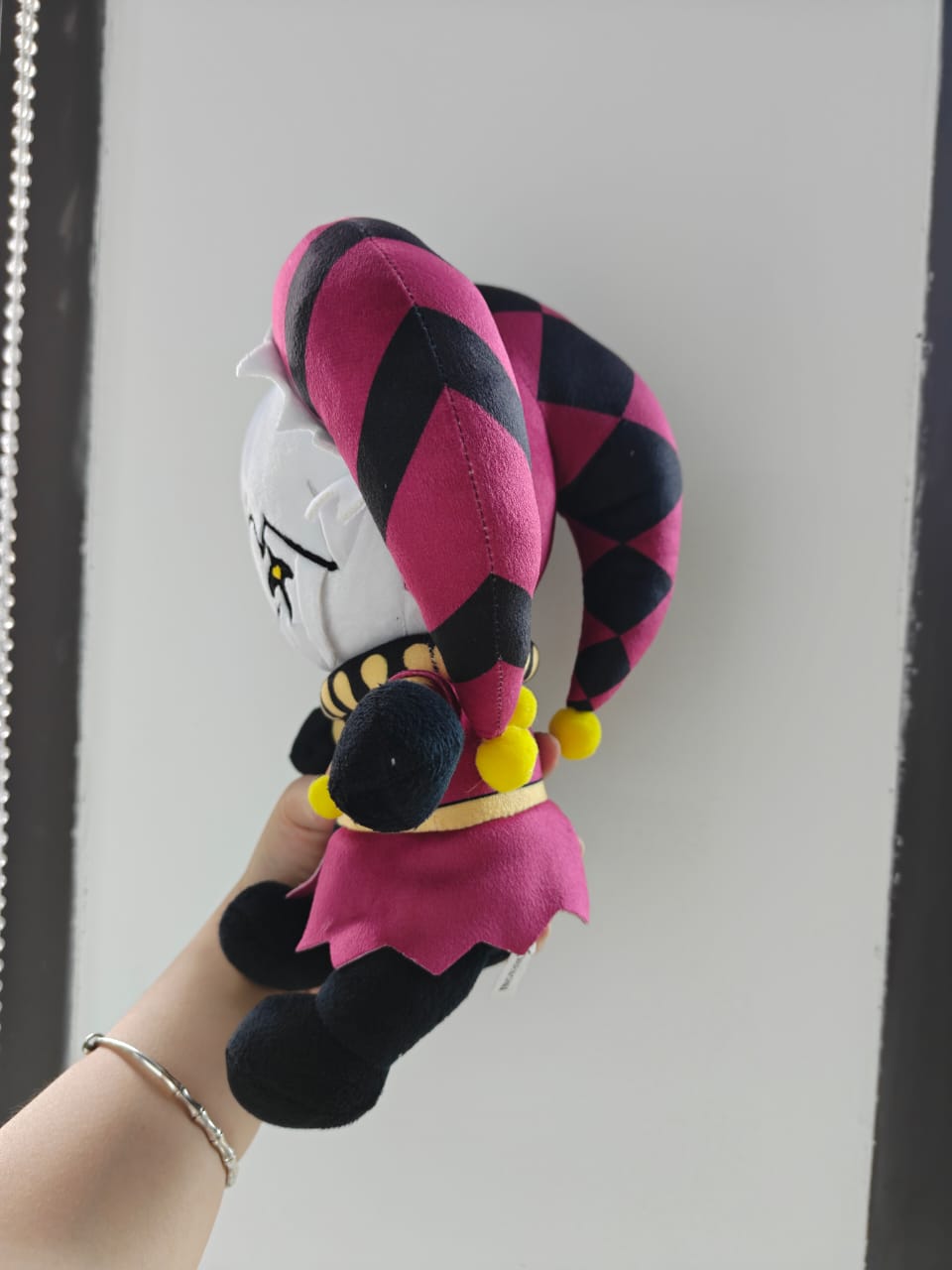 A detailed 25-centimeter handmade harlequin plush doll with circus horror elements, showcasing quality craftsmanship on a clean background.