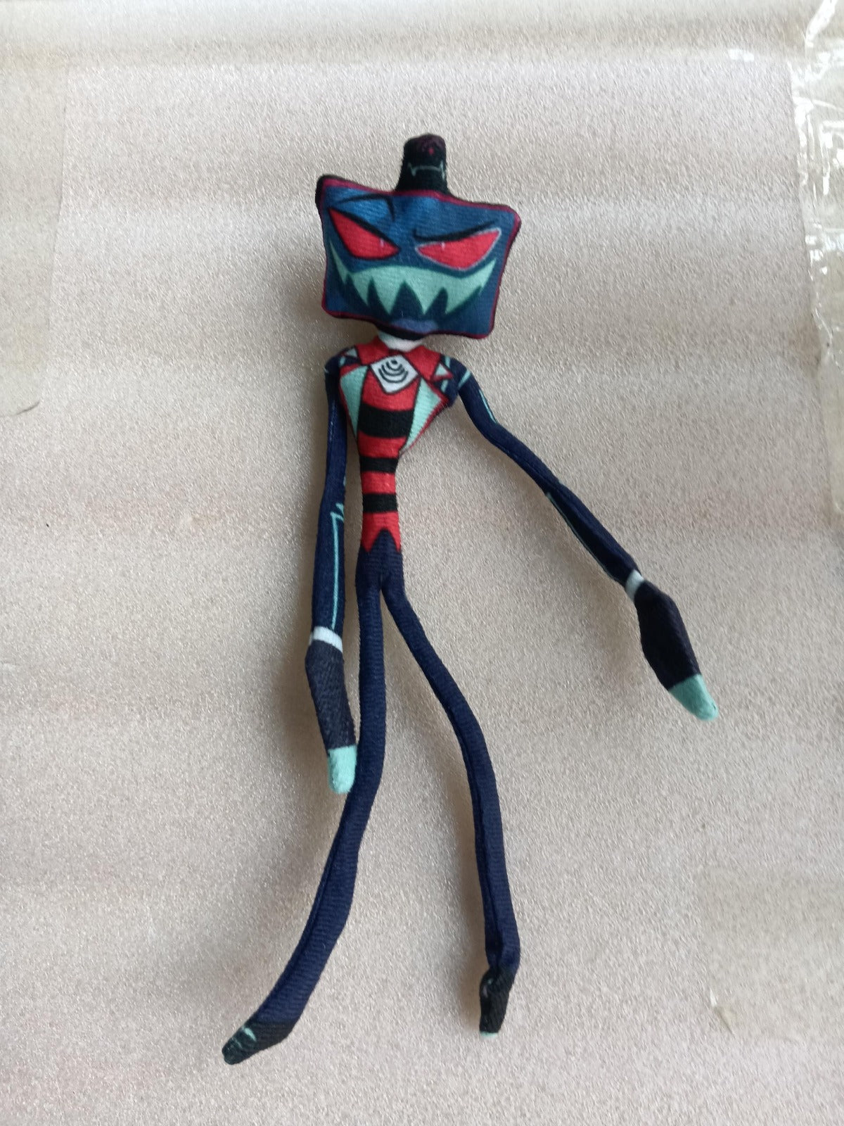 A_long-limbed_slender_skeleton-style_plush_toy_of_Vox_from_Hazbin_Hotel_posed_standing_in_front_of_a_blurred_outdoor_background_with_a_small_flowering_plant.supplier_update