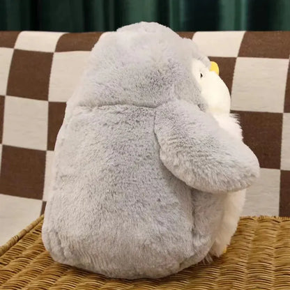 Adorable penguin plush sitting upright on a comfortable living room couch.