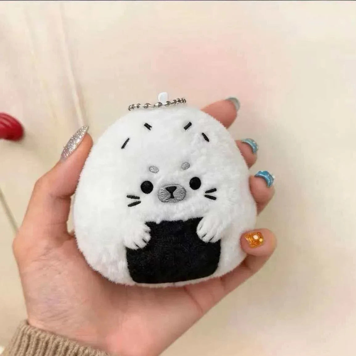 Baby seal plushie keychain attached to a pastel backpack zipper