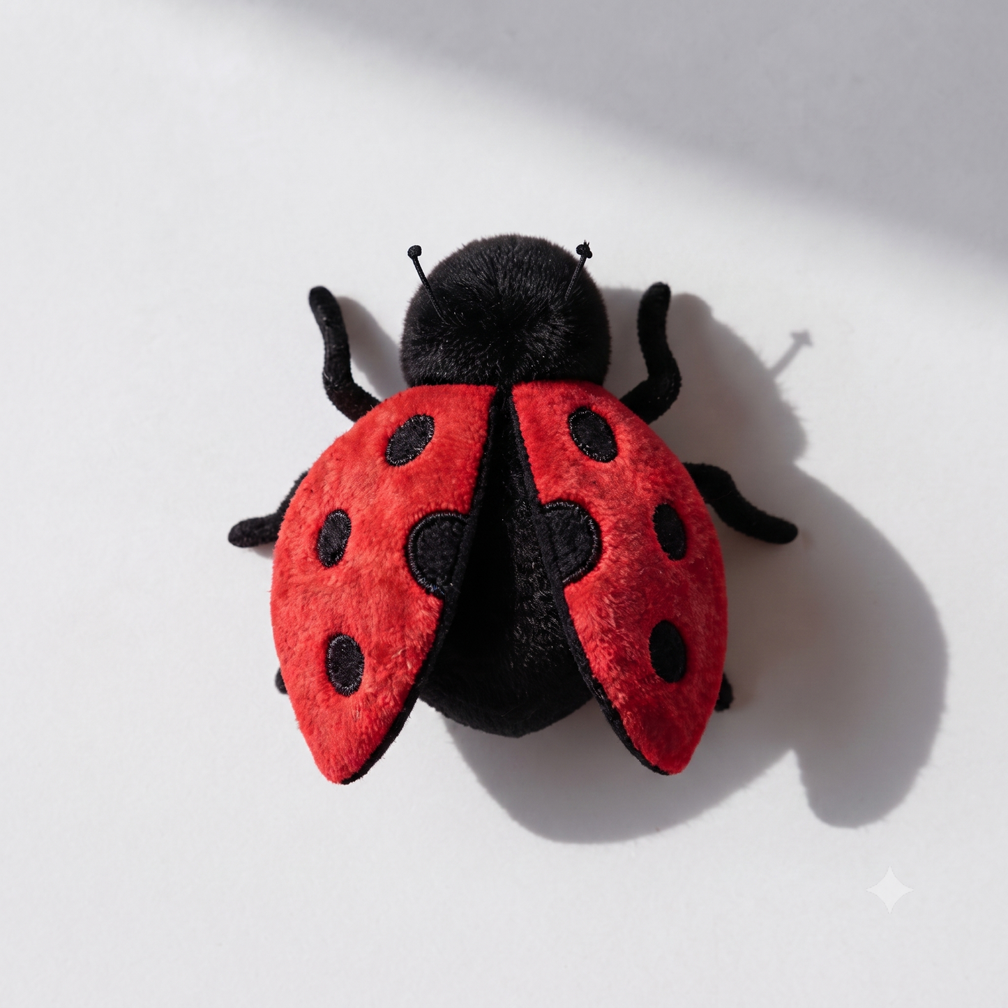 Butterfly plush toy 25cm wingspan spread flat on white surface next to smaller insect plushies