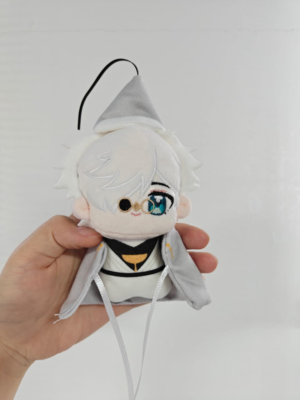 Close-up of fan-inspired witch master plush face showing white hair and blue eyes