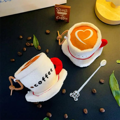 Cozy café plushie keychain styled on a wooden desk beside a coffee mug and open journal