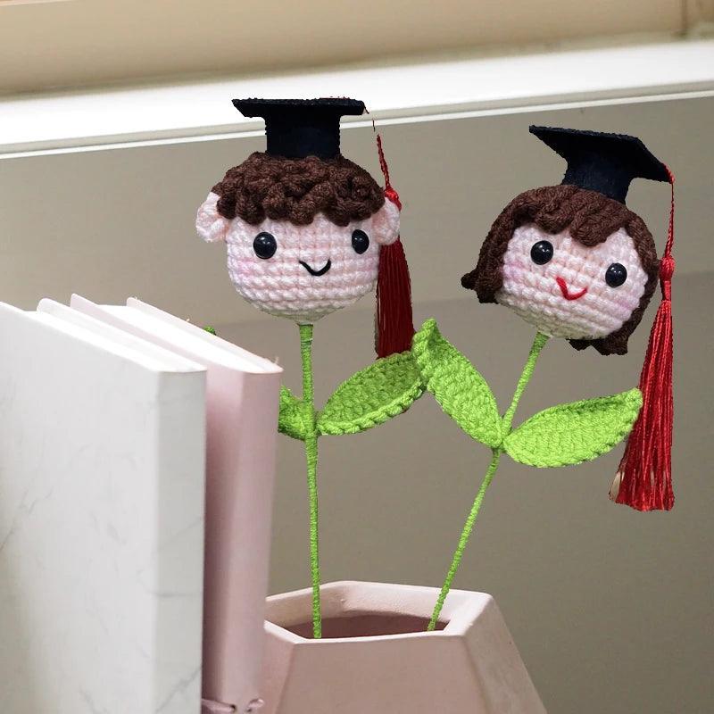 Crochet knitted flower graduation hat doll in white gown on white background

