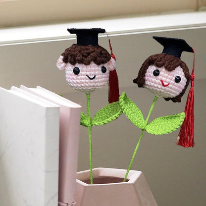 Crochet knitted flower graduation hat doll in white gown on white background
