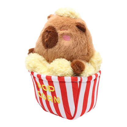 Cute capy stuffed toy in food-themed popcorn bucket on a desk