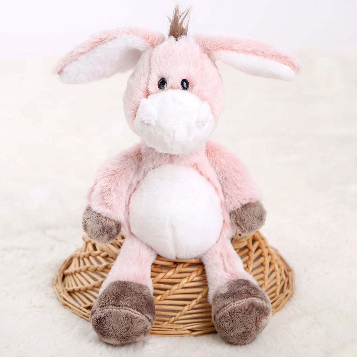 Cute donkey plushie placed beside a sleeping baby in a crib