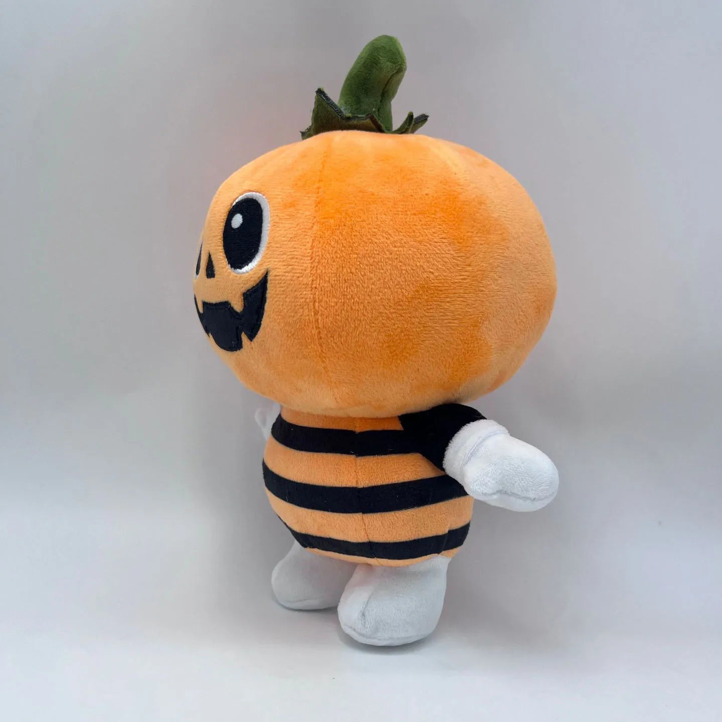 Cute pumpkin plushie sitting on autumn fall decor shelf