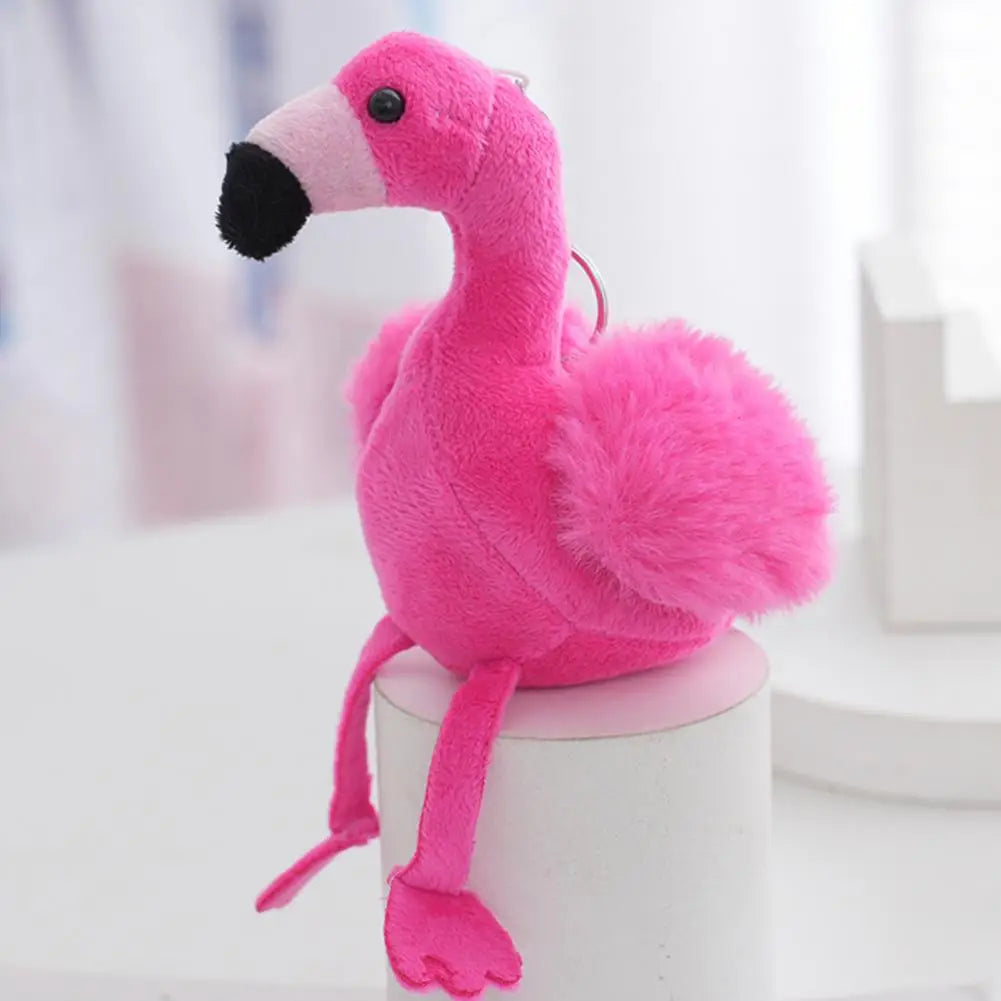 Flamingo stuffed key chain baby pink colorway clipped to a tan leather bag handle close up