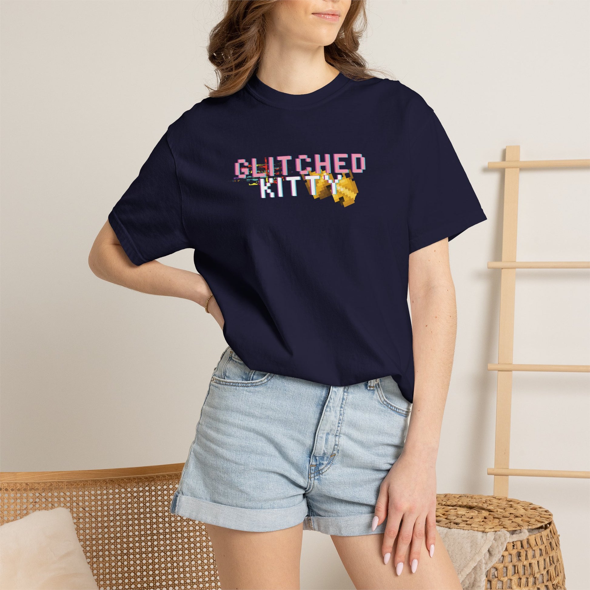 Flat lay arrangement of the glitched kitty tee with retro gaming accessories and pixel art stickers