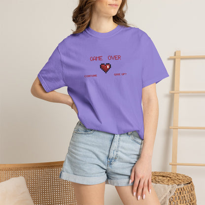 Flat lay of gamer gift tee on a dark wooden surface with soft raking side light showing graphic placement and color tone
