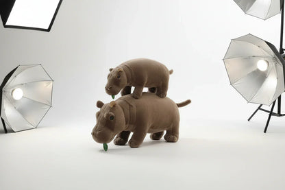 Front view of the soft plush moo deng sitting on a bed