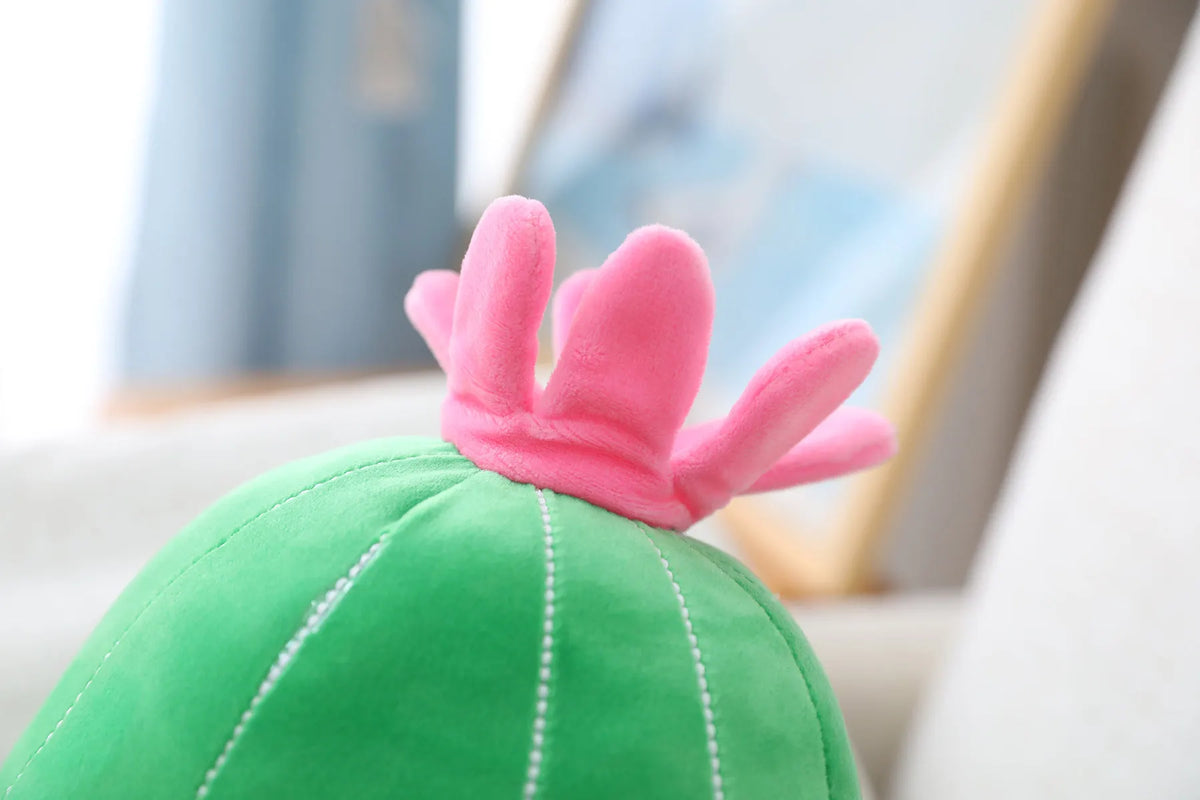 Full body view of the green kawaii cactus stuffed pillow against a pastel background