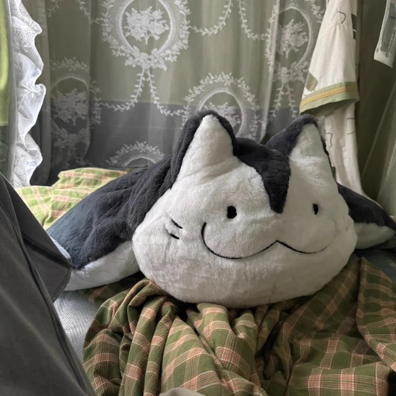 Giant manta ray stuffed animal displayed as decorative cushion on grey sofa