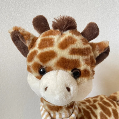 Giraffe toy with striped scarf showing full height and plush texture detail
