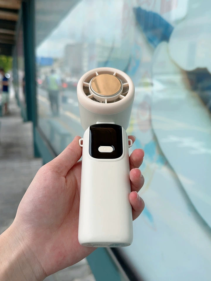 Handheld cooling fan folded flat next to smartphone showing compact pocket size

