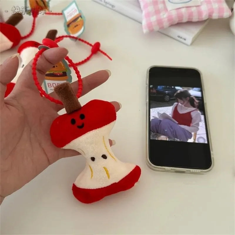 Handheld view of a soft pendant key chain shaped like an eaten apple