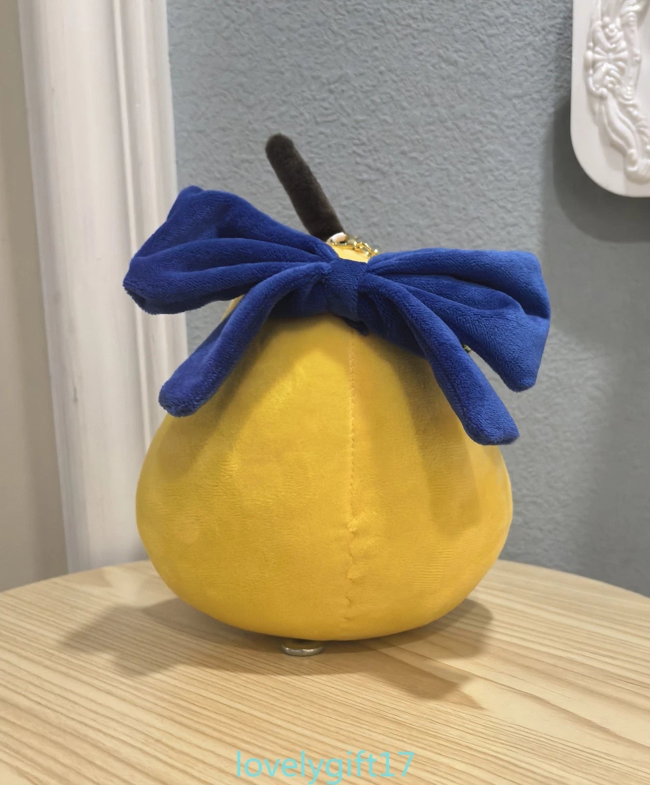 Yellow plush toy with a blue bow on a wooden surface