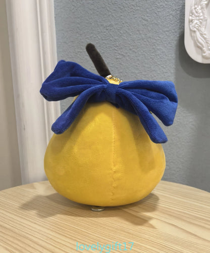 Yellow plush toy with a blue bow on a wooden surface