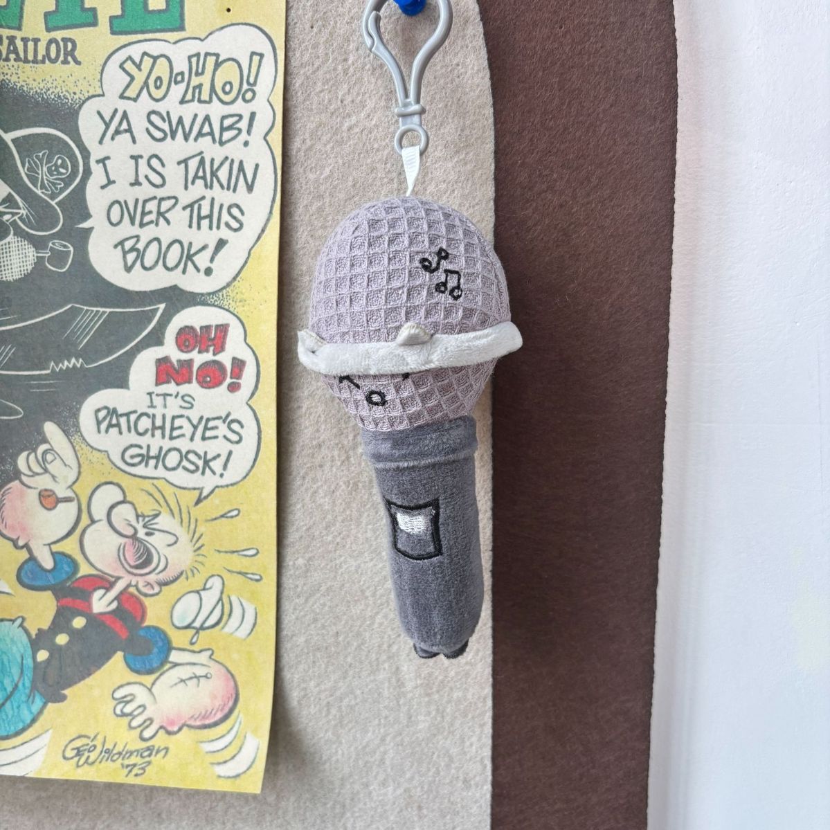 Mic plush bag charm clipped to backpack strap lifestyle shot