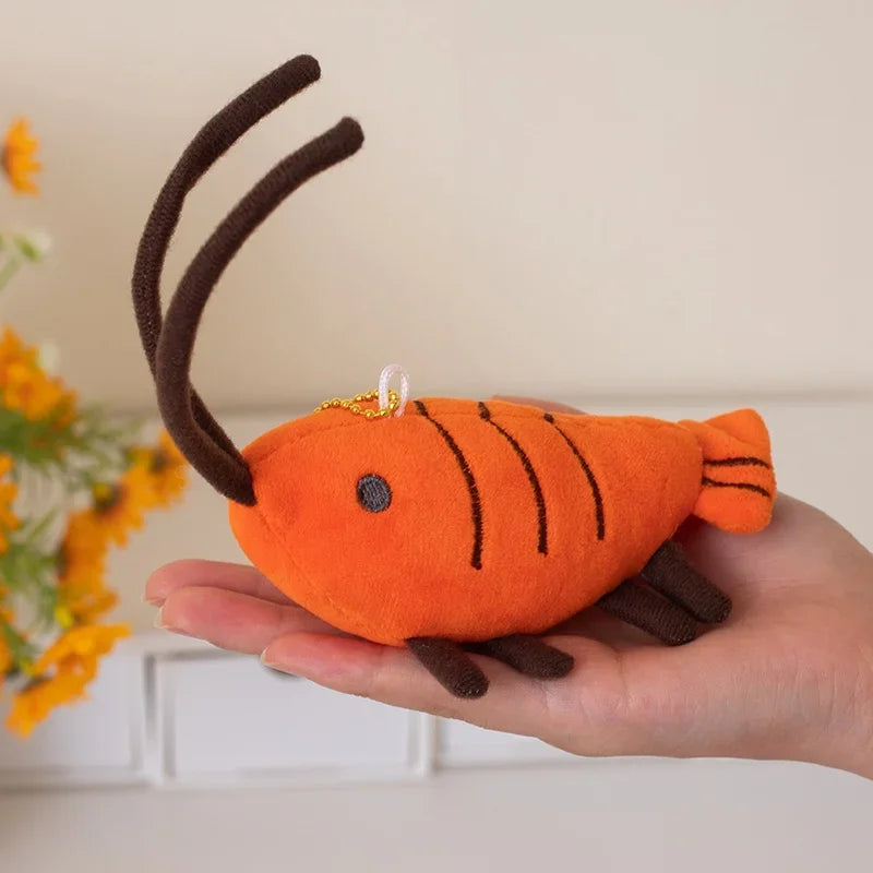 Orange prawn stuffed animal keychain hanging on a backpack strap