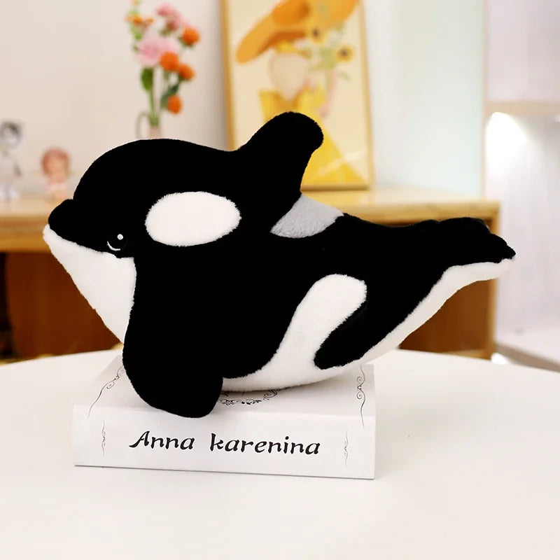 Orca plushie on bookshelf alongside other kawaii stuffed animals