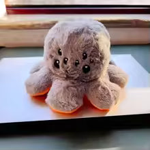 Pair of hands flipping the pumpkin plush inside out to transform it into the spider mood plushie, step by step view