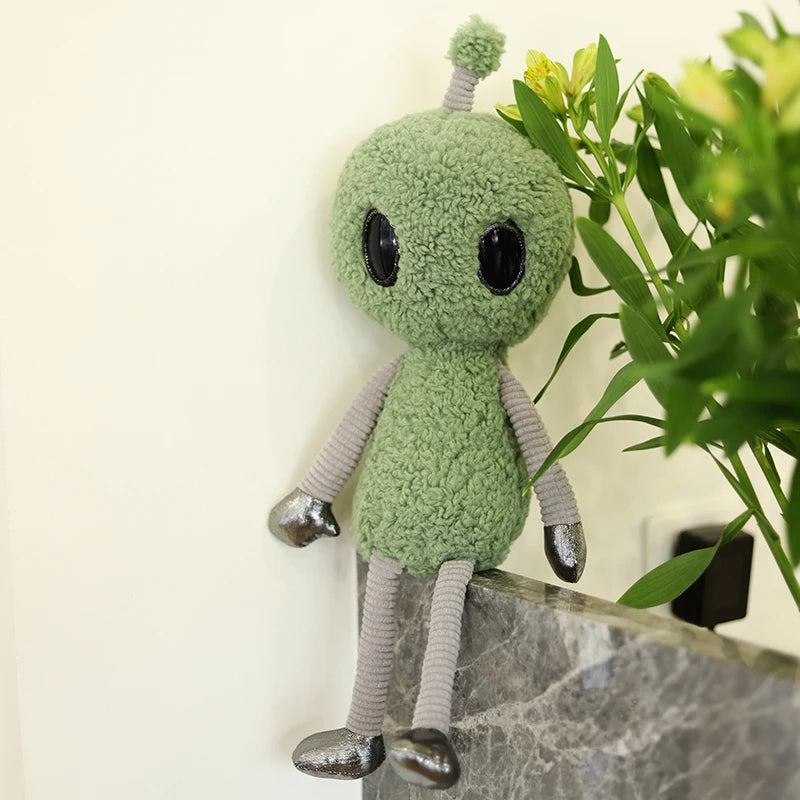 Pastel goth alien plush in purple colorway draped softly over decorative pillow