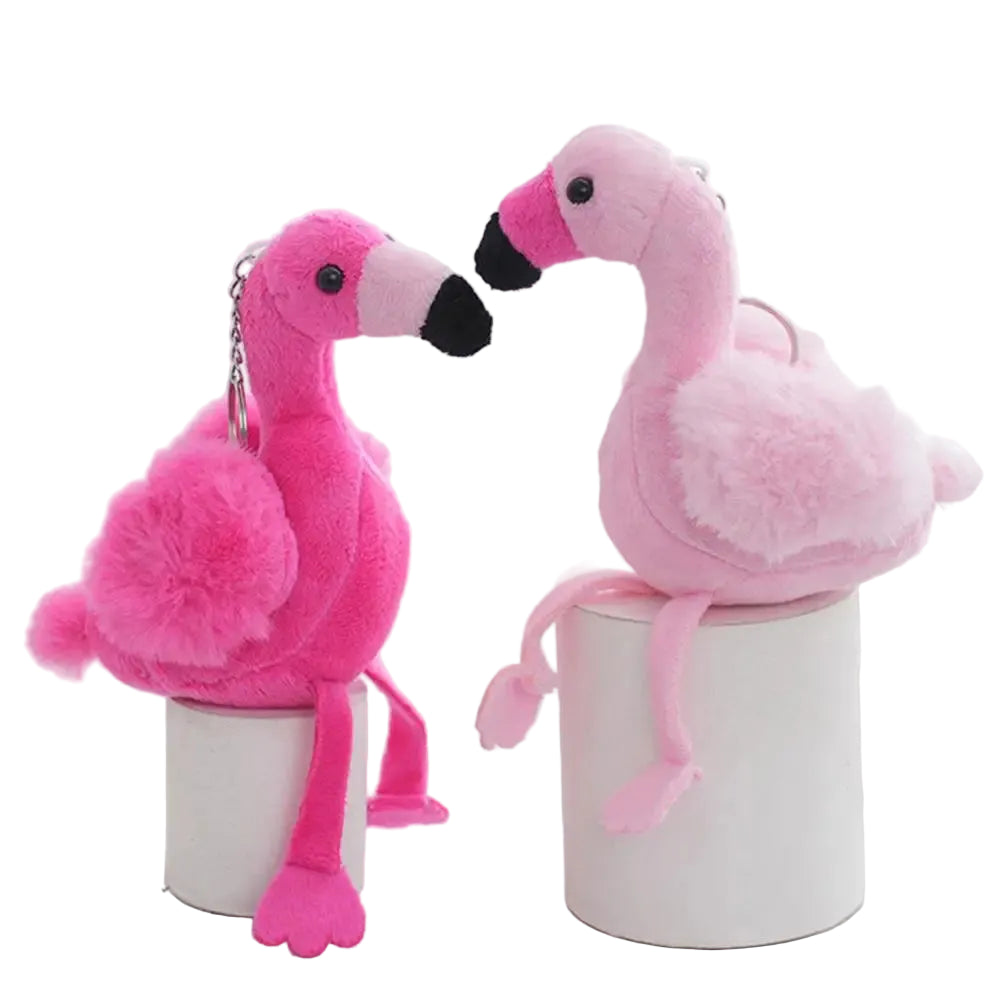 Pink flamingo plushie keychain charm in bold pink colorway hanging from a navy backpack zipper