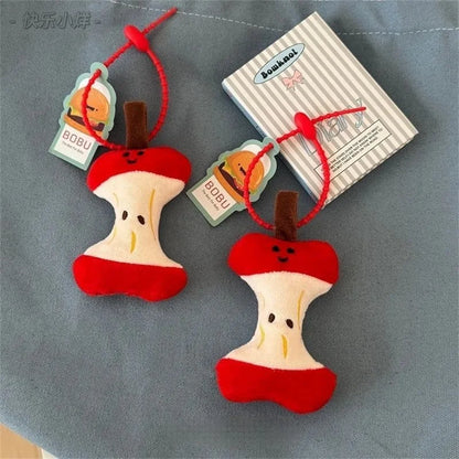 Red apple key chain hanging from a designer denim backpack