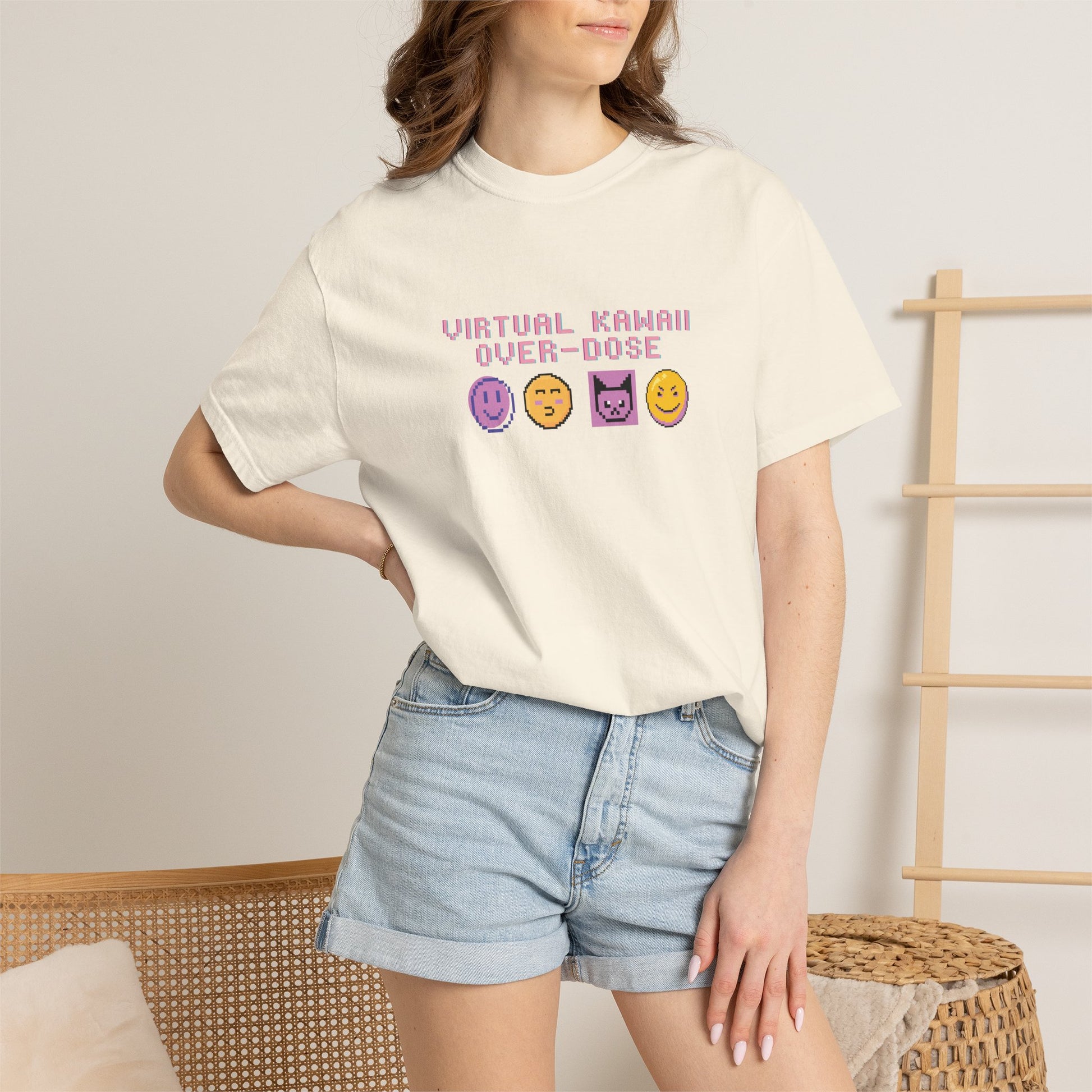 Retro pixel emoji tee folded next to a handheld console and headphones
