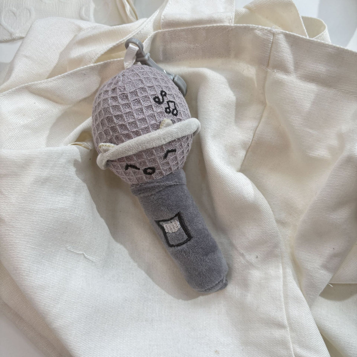 Singing mic plush showing embroidered musical notes detail on body