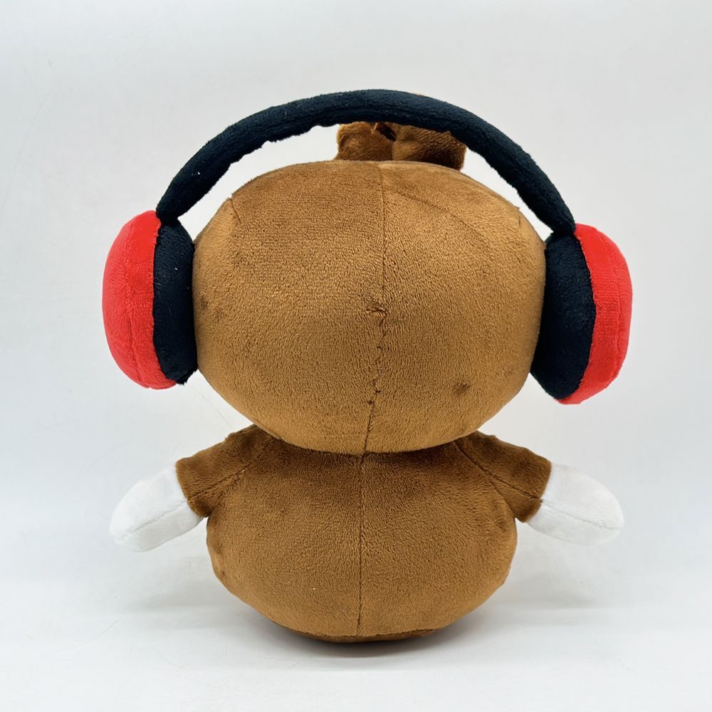 Soft handmade monkey plush toy with red headphones top down view