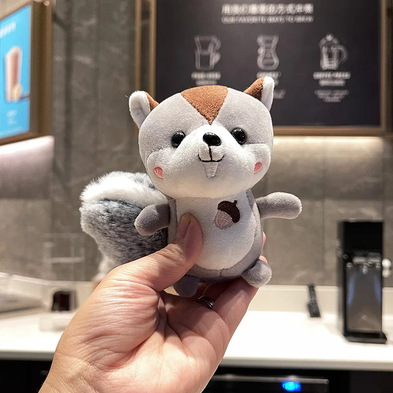Soft squirrel toy keychain clipped to canvas backpack strap