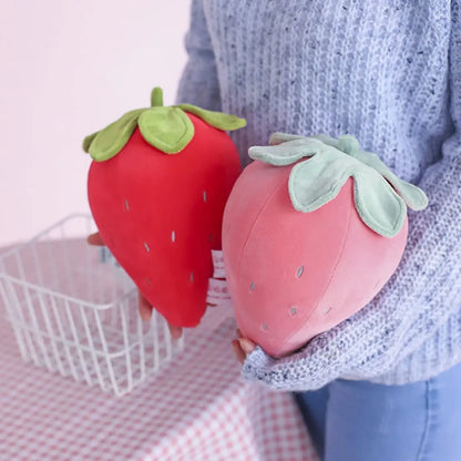 Strawberry stuffed animal sitting upright on wooden shelf
