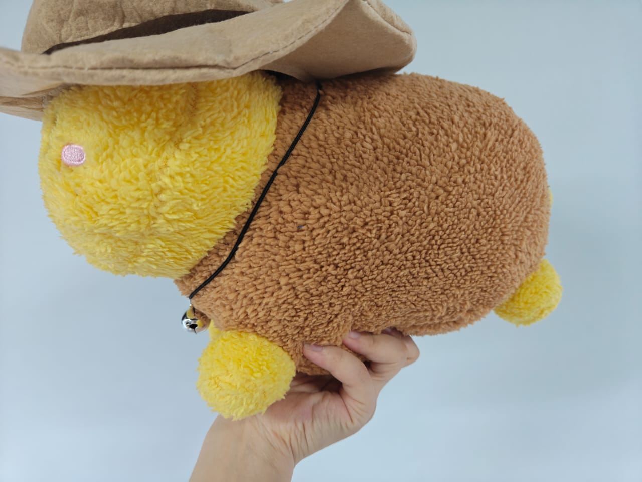 Thomas HWWHP plush placed on a bed pillow in a warmly lit, casual room.