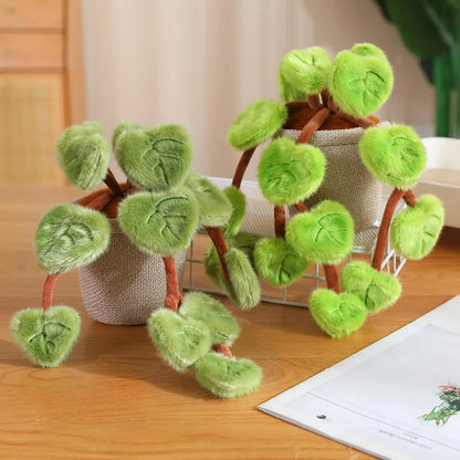 Trailing vine plant plush draped over bookshelf edge beside candles