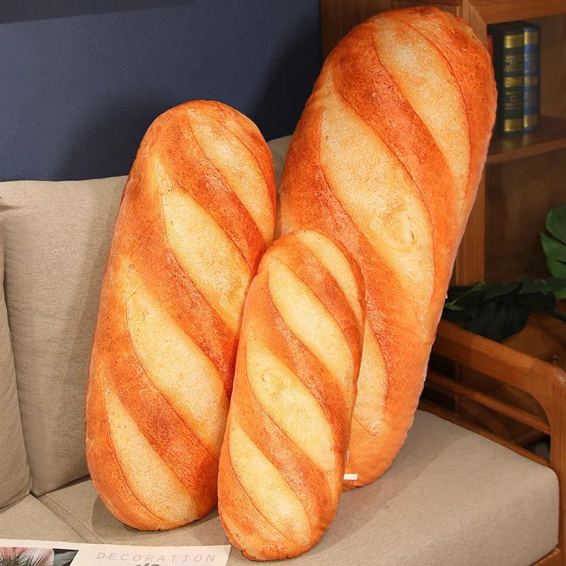 Two large bread-shaped pillows on a couch with a bookshelf in the background.