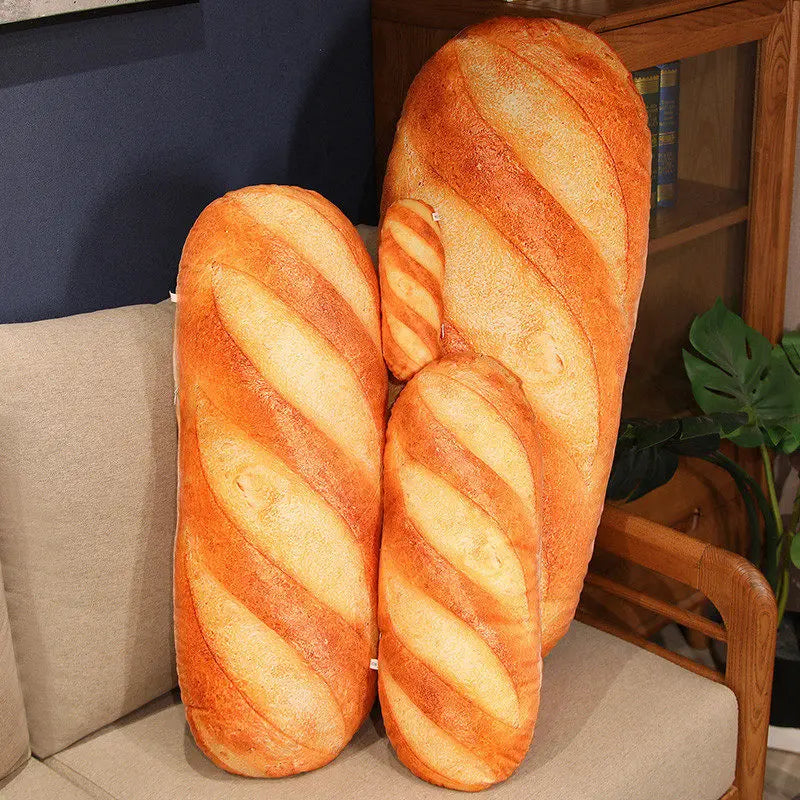 Two loaf-shaped pillows on a couch with a bookshelf and plant in the background.